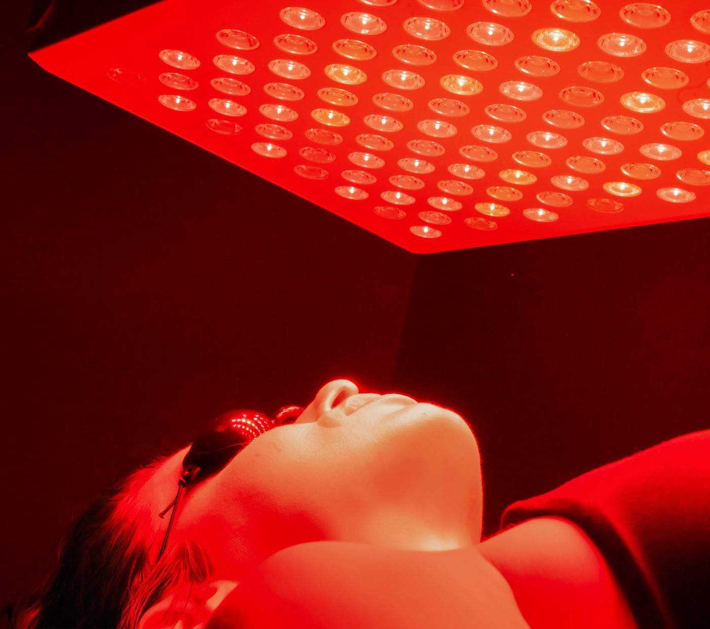 A member lying beneath the medical-grade red light and near-infrared panel at Your Journey Health Club, wearing protective eyewear